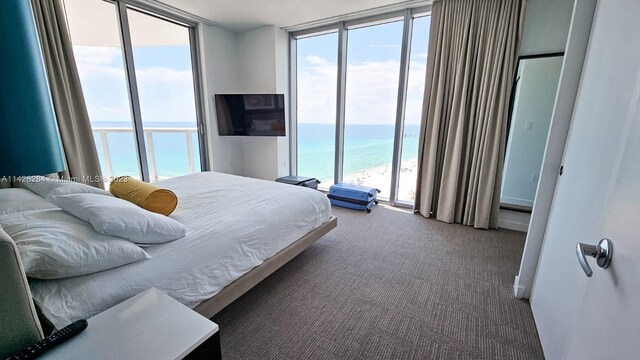 bedroom with carpet flooring, floor to ceiling windows, multiple windows, and a water view