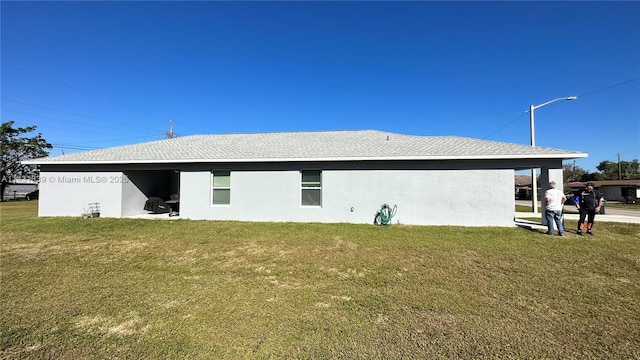 rear view of house with a yard and stucco siding