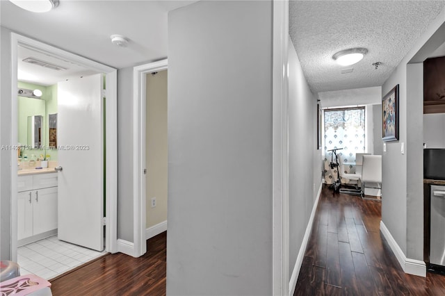 corridor with a textured ceiling and dark tile floors