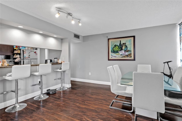 interior space with track lighting, a textured ceiling, and dark hardwood / wood-style floors