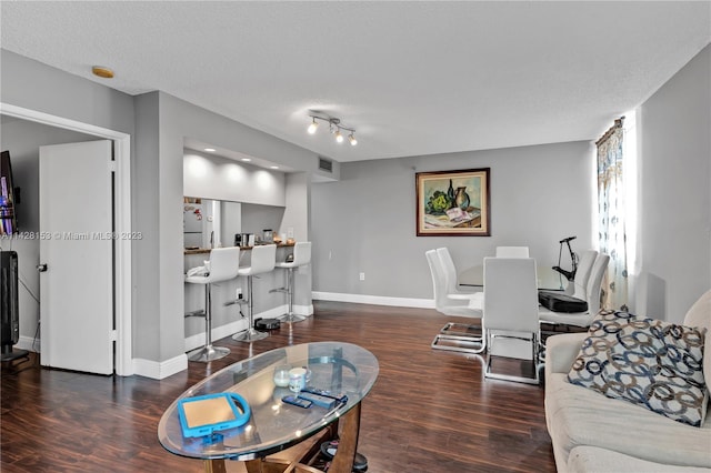 living room with rail lighting, dark hardwood / wood-style flooring, and a textured ceiling