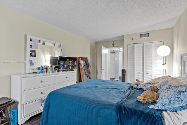 bedroom with a closet, a textured ceiling, and dark hardwood / wood-style floors