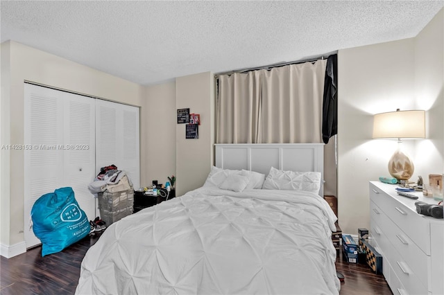 bedroom with a closet, a textured ceiling, and dark hardwood / wood-style floors