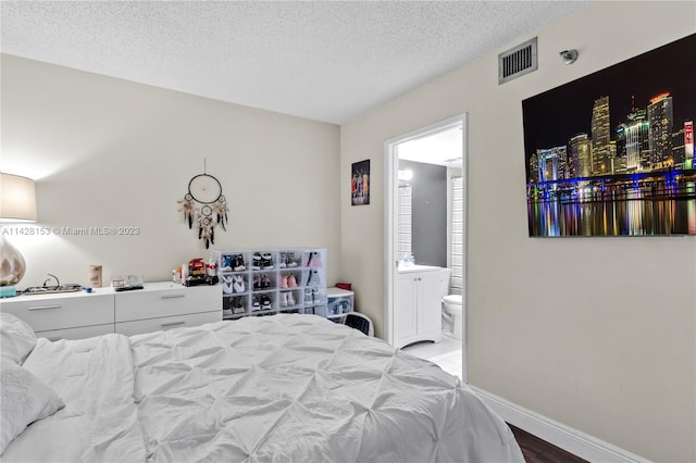 bedroom featuring connected bathroom, light hardwood / wood-style flooring, and a textured ceiling