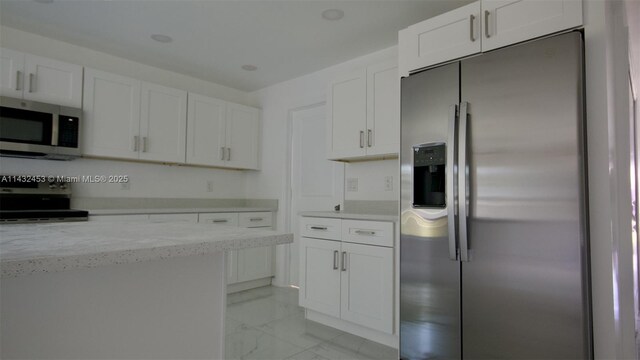 3433 Jeffcott St, Fort Myers, FL 33916 - kitchen with marble finish floor, white cabinetry, stainless steel appliances, and light stone countertops