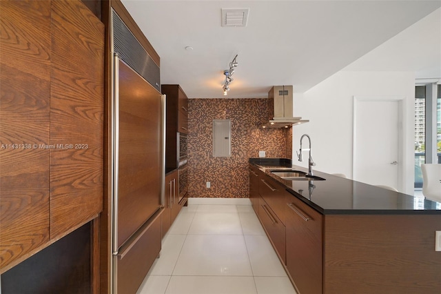 kitchen featuring sink, light tile floors, island exhaust hood, rail lighting, and backsplash