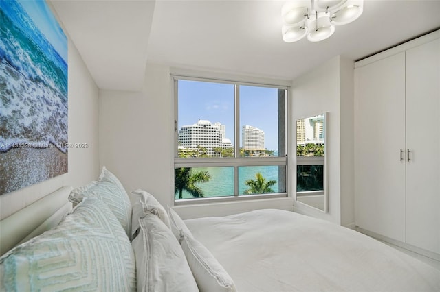 bedroom featuring an inviting chandelier and a water view