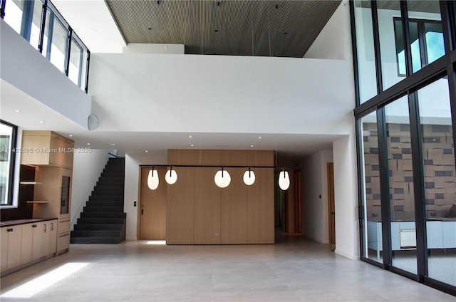 11500 SW 60th Ave, Pinecrest, FL 33156 - unfurnished living room featuring a high ceiling, healthy amount of natural light, light tile patterned flooring, stairway, and floor to ceiling windows