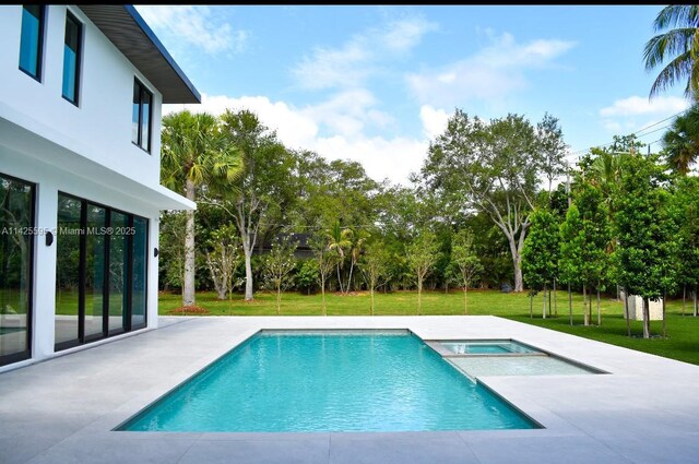 11500 SW 60th Ave, Pinecrest, FL 33156 - view of swimming pool with a yard, a patio, a pool with connected hot tub, and view of scattered trees