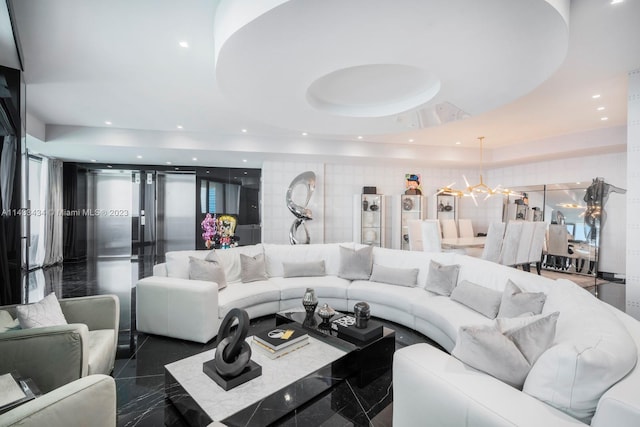 living room featuring tile walls, a tray ceiling, dark tile floors, and an inviting chandelier