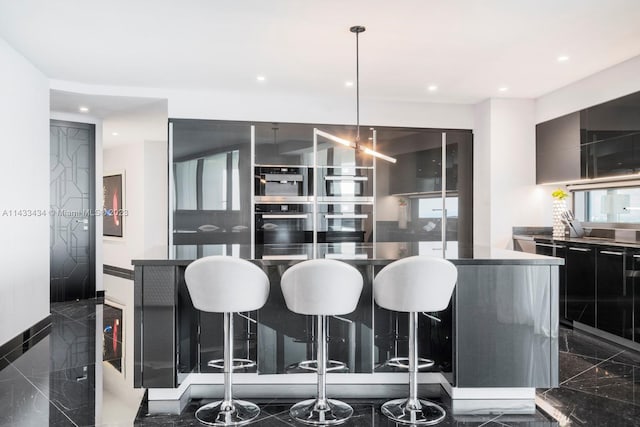 kitchen featuring pendant lighting, a center island, a breakfast bar area, and dark tile flooring