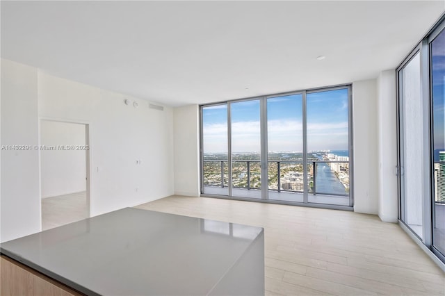 interior space featuring plenty of natural light, a water view, expansive windows, and light wood-type flooring