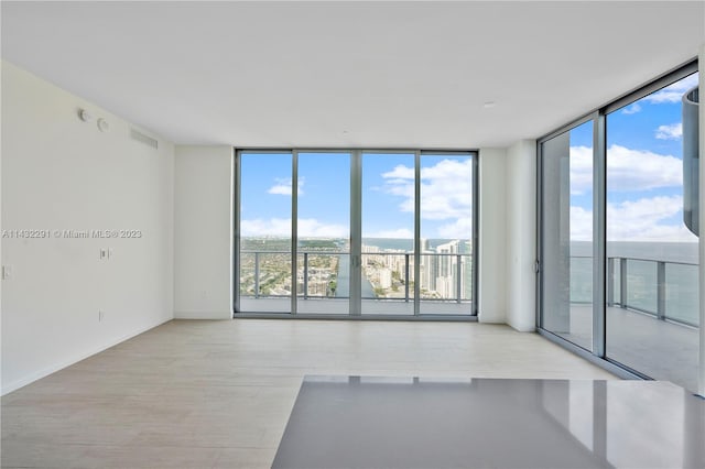 unfurnished room featuring floor to ceiling windows and light hardwood / wood-style flooring