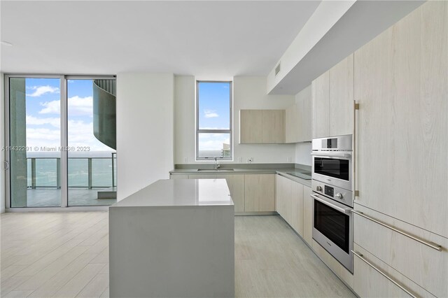 kitchen with a center island, light hardwood / wood-style flooring, expansive windows, and stainless steel oven