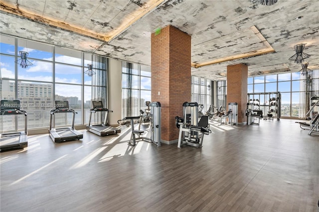 gym with brick wall, floor to ceiling windows, and hardwood / wood-style floors