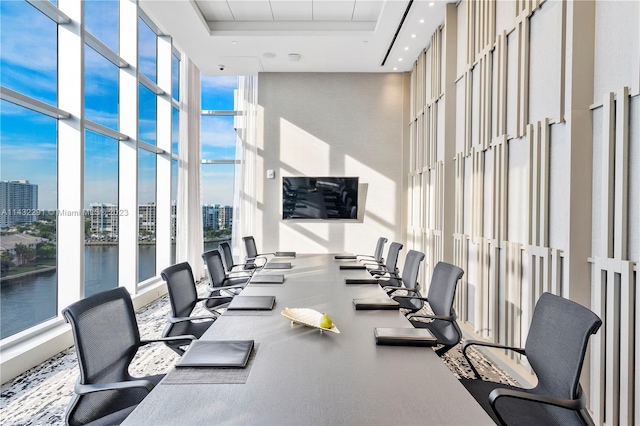 gym featuring french doors, a towering ceiling, a water view, a wall of windows, and a tray ceiling