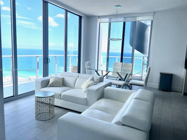 living room featuring a water view, a wall of windows, and light hardwood / wood-style flooring