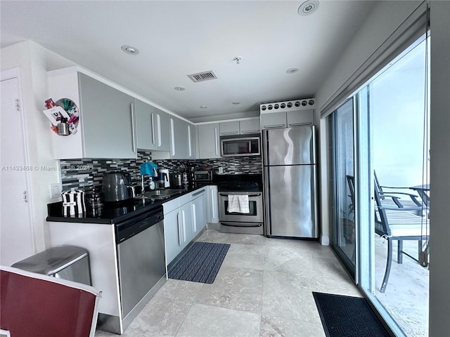 kitchen with gray cabinetry, decorative backsplash, sink, and stainless steel appliances