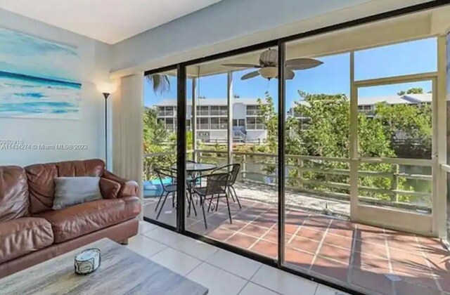 doorway featuring ceiling fan, light tile floors, and a wealth of natural light