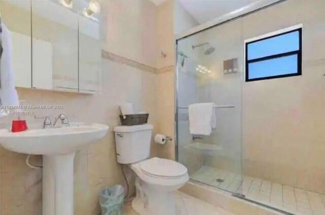 bathroom with toilet, a shower with shower door, and tile flooring