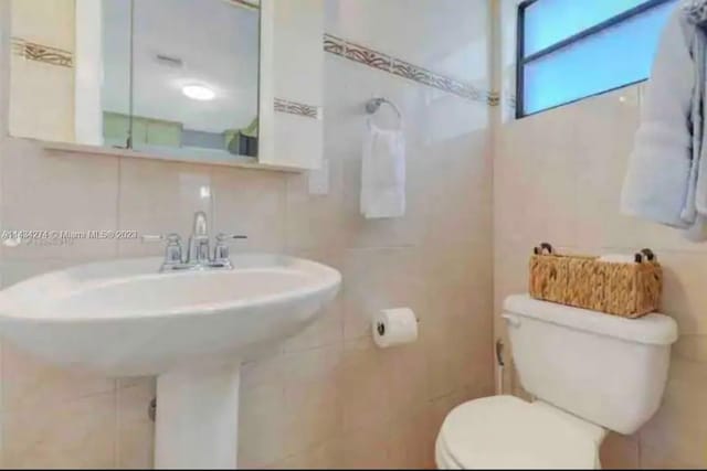 bathroom featuring tile walls, toilet, and tasteful backsplash