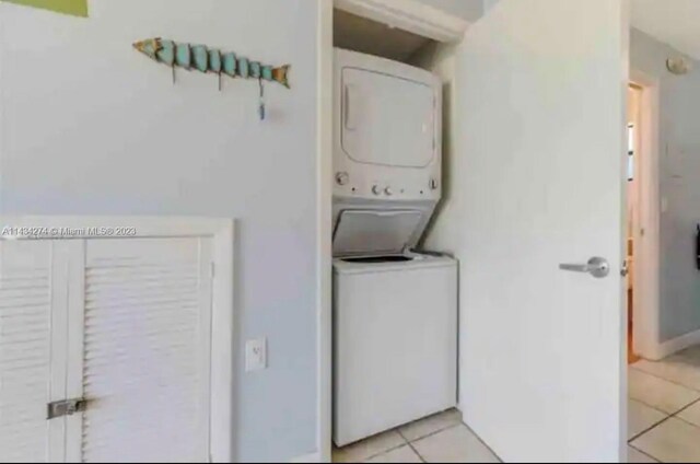 laundry room featuring stacked washer / drying machine and light tile floors