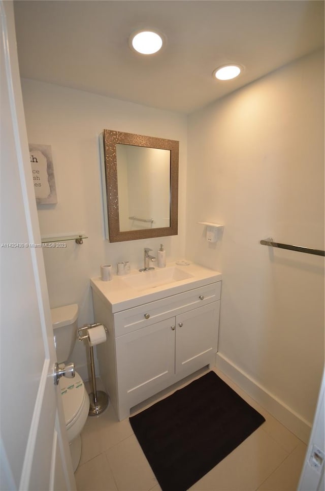 bathroom with toilet, vanity with extensive cabinet space, and tile floors