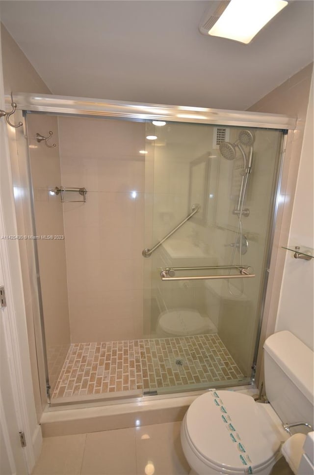 bathroom with an enclosed shower, toilet, and tile flooring