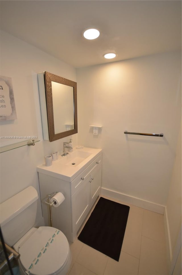 bathroom featuring toilet, vanity, and tile flooring