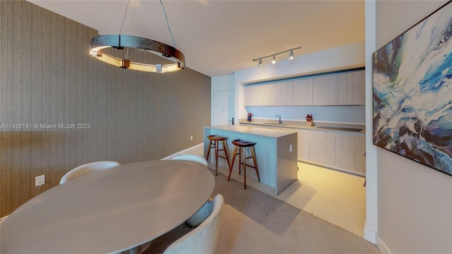 tiled dining room featuring rail lighting and sink