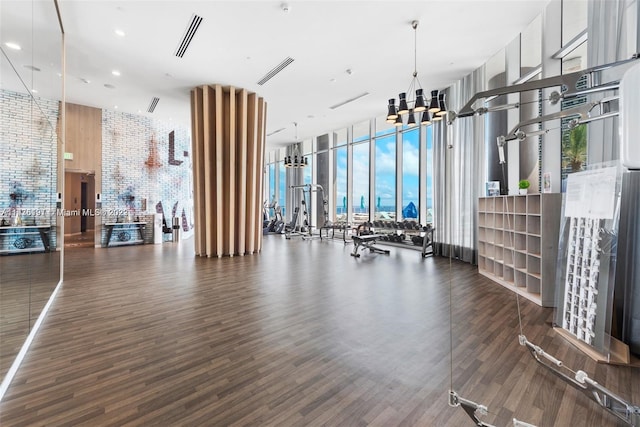 gym with a wall of windows, a notable chandelier, and dark hardwood / wood-style flooring