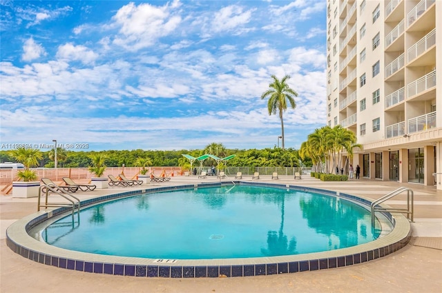 community pool with a patio area and fence