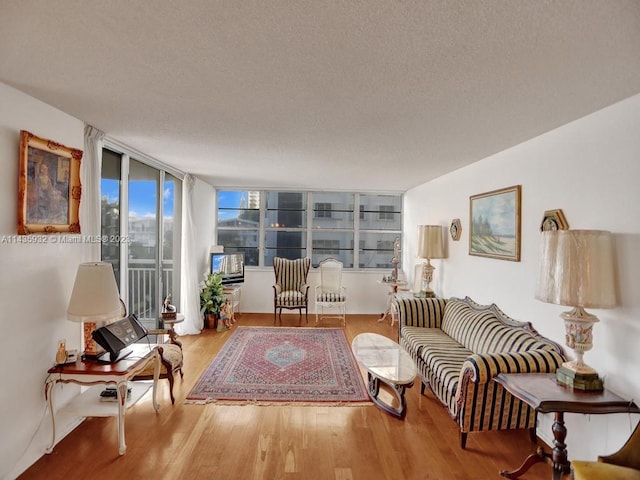 living room with a textured ceiling, a wall of windows, and light hardwood / wood-style flooring