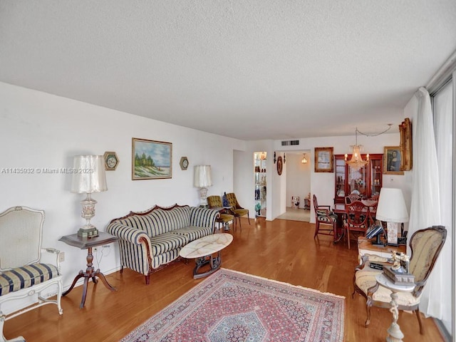 living room with an inviting chandelier, a textured ceiling, and hardwood / wood-style floors