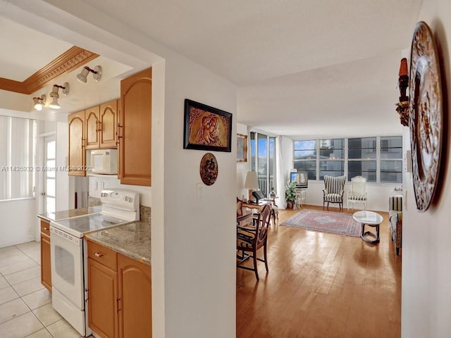 kitchen with light tile flooring, light stone countertops, white appliances, and plenty of natural light