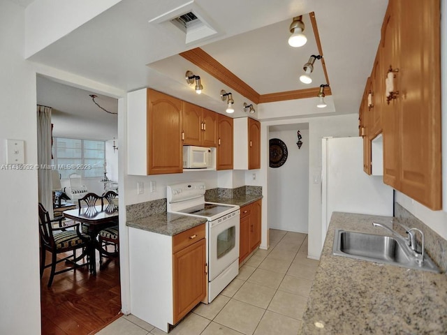 kitchen featuring light hardwood / wood-style floors, dark stone counters, white appliances, a raised ceiling, and sink