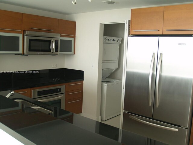 kitchen with appliances with stainless steel finishes and stacked washer and clothes dryer