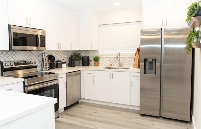 kitchen featuring backsplash, light hardwood / wood-style floors, stainless steel appliances, and white cabinets