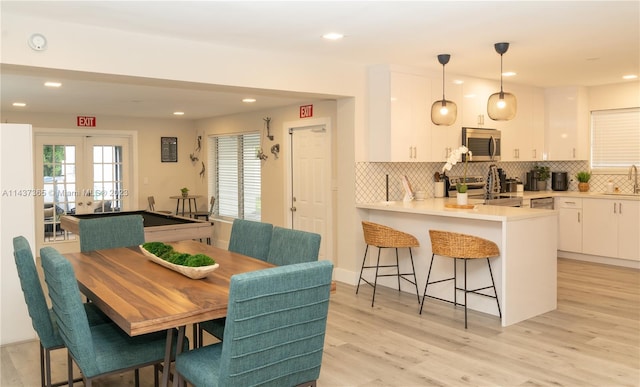 dining space featuring french doors, sink, and light wood-type flooring