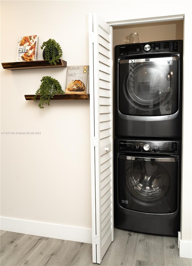 laundry area featuring stacked washing maching and dryer and light wood-type flooring