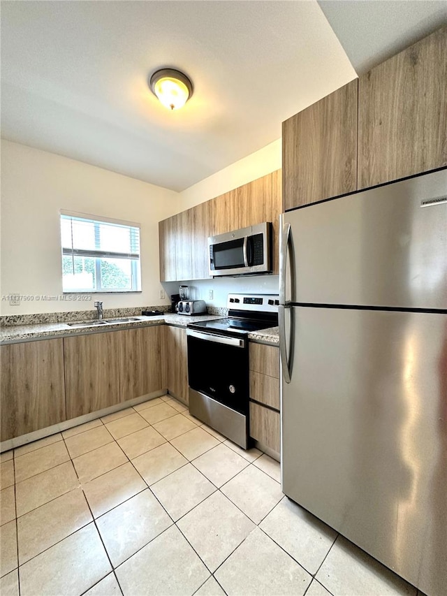 kitchen featuring stainless steel appliances, light tile flooring, and sink