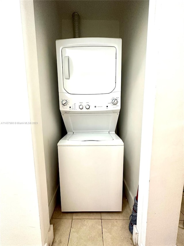 clothes washing area featuring stacked washer / dryer and light tile floors