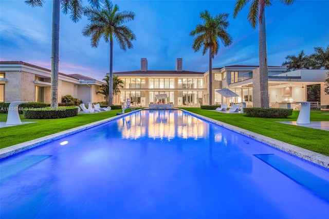 pool at dusk featuring a yard