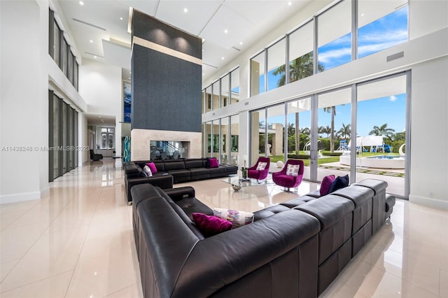 living room with a high ceiling, light tile floors, french doors, and a multi sided fireplace