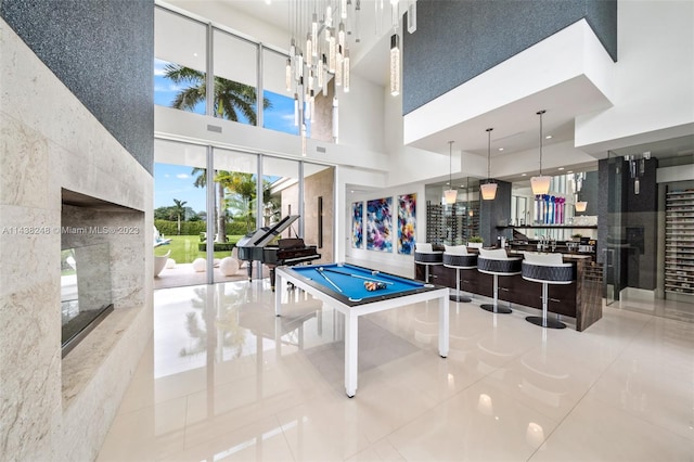 rec room with light tile floors, pool table, and a towering ceiling