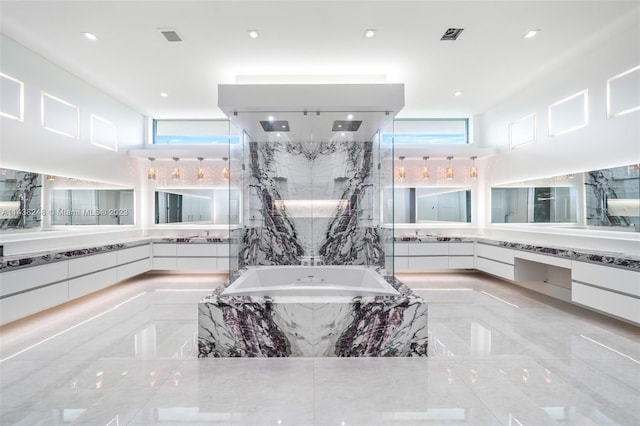 bathroom featuring tiled tub, vanity with extensive cabinet space, and tile flooring