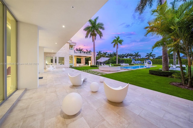 patio terrace at dusk featuring a lawn