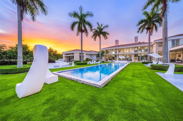 pool at dusk with a yard and a patio