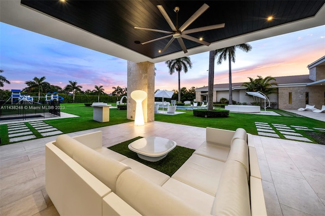 patio terrace at dusk with a swimming pool, an outdoor hangout area, a yard, and ceiling fan