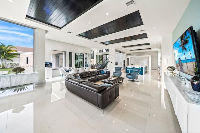 living room with light tile floors, a tray ceiling, and a wealth of natural light